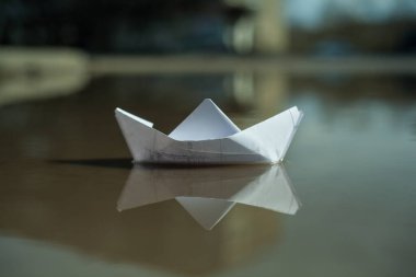 Kağıttan bir tekne şehirdeki bir dere boyunca yelken açar.