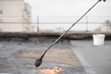 Çatının tamiri açık bir gaz alevi, çatıda eski hırpalanmış ekipmanlar.