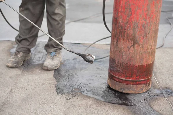 作業員は古い作業靴の中で開いた炎でガスボンベを暖める ガス圧を上昇させるための安全規制違反 — ストック写真