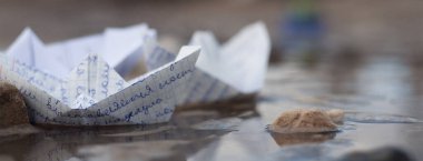 Çamurlu bir su birikintisinde kağıt gemilerin deniz savaşı