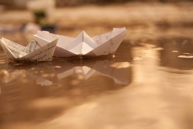 Bir su birikintisinde yüzen, defter çarşafından beyaz bir tekne.