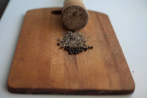 黑胡椒豌豆用木制砂浆磨碎在厨房的切菜板上 — 图库照片