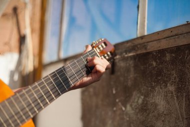 Güneşli bir günde evde gitar çalmak.