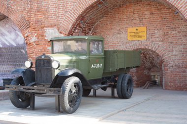 Kırmızı tuğladan kale duvarının arkasında eski modelin askeri donanımı var..
