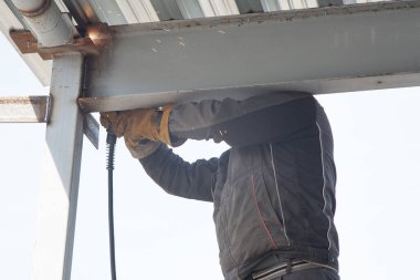 Elektrik kaynakçısı, inşaat alanında elektrik kaynağı, metal yapıların kurulumunda yarı otomatik elektrik kaynağı.