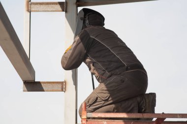 Elektrik kaynakçısı, inşaat alanında elektrik kaynağı, metal yapıların kurulumunda yarı otomatik elektrik kaynağı.