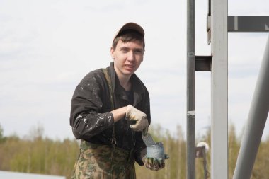 Genç bir adam metalci olarak çalışıyor, gri diş minelerini boyuyor..