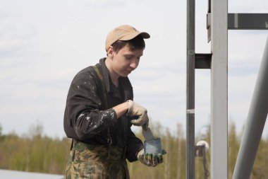 Genç bir adam metalci olarak çalışıyor, gri diş minelerini boyuyor..