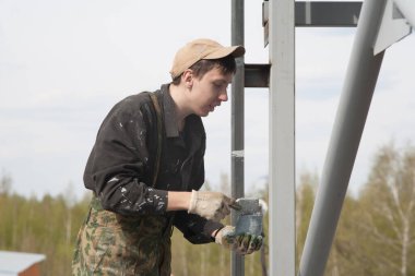 Genç bir adam metalci olarak çalışıyor, gri diş minelerini boyuyor..