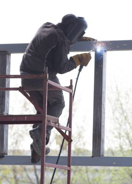 Elektrikli kaynakçı güneşli bir günde metal yapıları kaynak yapar