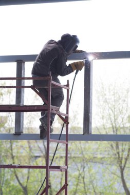 Elektrikli kaynakçı güneşli bir günde metal yapıları kaynak yapar