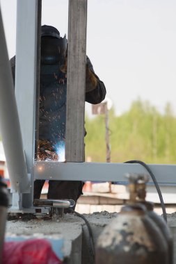 Elektrikli kaynakçı güneşli bir günde metal yapıları kaynak yapar