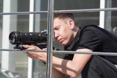 İşteki fotoğrafçı, fotoğrafçı görüntüleri kontrol ediyor, fotoğrafçı yan taraftan bakıyor.