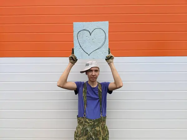 Killen Håller Affisch Med Ett Målat Hjärta Vit Orange Bakgrund — Stockfoto