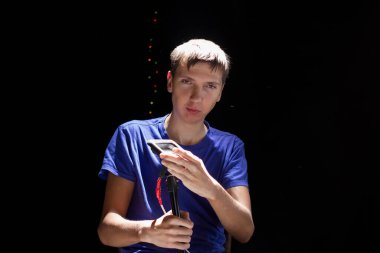 Elinde fenerler olan genç bir elektrikçi, siyah bir arka plan üzerinde çalışıyor. Adam karanlık bir arka planda LED ışıkları tutuyor..