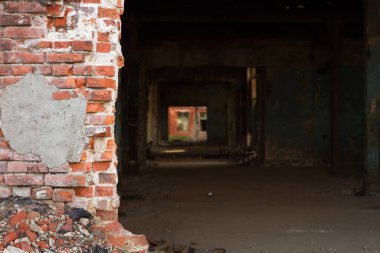 Harap olmuş tuğla ve endüstriyel bir binada bir tünel. Kırmızı tuğladan bir duvar ve binanın yakınında bir geçit..