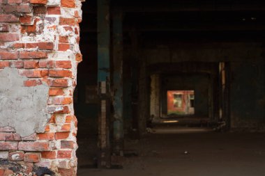 Kırmızı tuğladan bir duvar ve binanın yakınında bir geçit. Harap olmuş tuğla işi. Endüstriyel bir binada tünel..