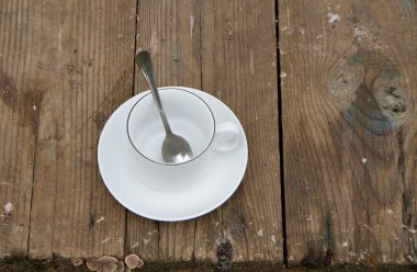 Beyaz bir fincan eski bir ahşap masanın üzerinde boş duruyor. Gövde üzerinde beyaz bir fincan eski bir ahşap masada duruyor..