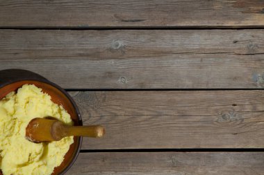 Eski ahşap bir masada patates pişirmek. Tahta bir masada, sarı bir tencerede çiğ patates. Eski tahta tahtalar ve sebzeler.