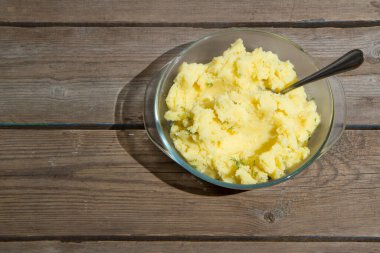 Eski ahşap bir masada patates pişirmek. Tahta bir masada, sarı bir tencerede çiğ patates. Eski tahta tahtalar ve sebzeler.