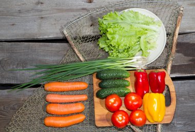Sebzeler masanın üstünde. Eski çam ağacından yapılmış eski bir masanın üzerinde taze çiğ sebzeler yatıyor..