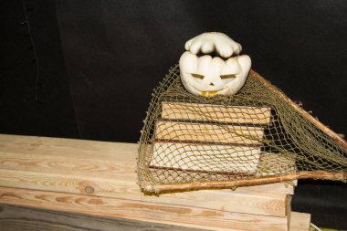 Jack O'Lantern. Yanan gözlü bir balkabağı. Eski kitapların arka planına karşı eski bir tahta masada Cadılar Bayramı için bir balkabağı..