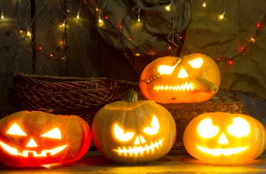 Cadılar Bayramı için yanan çelenkleri olan bir dolabın arka planında balkabağı feneri..