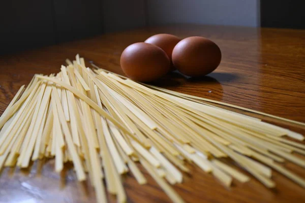 Taze yumurtalı makarna. Tahta tahtada spagetti ve tavuk yumurtası. Spagetti pişirmek için gerekli malzemeler..