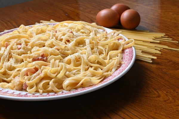 Lezzetli bir tabak rendelenmiş peynirli spagetti. İçinde malzemeler olan bir tabak taze makarna. Makarna ve yumurtalı makarna..