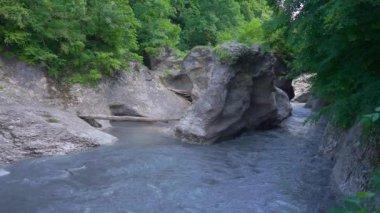 Khadzhokh vadisi. Belaya Nehri 'nin sonundaki vadiye bakın. Taş sütunların nehri iki kanala ayırdığı görülebilir. Biraz bulutlu. Güneş bulutların arkasında kayboldu..