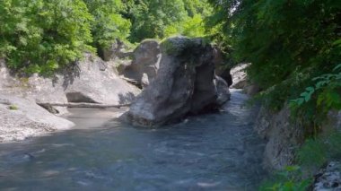 Khadzhokh vadisi. Belaya Nehri 'nin sonundaki vadiye bakın. Taş sütunların nehri iki kanala ayırdığı görülebilir. Hava güneşli. Gölgeler suya düştü..