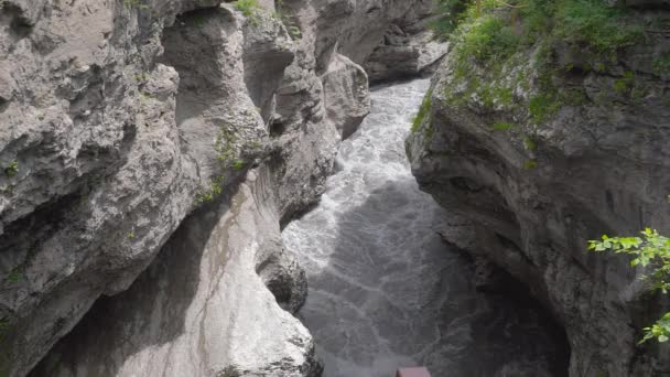 Khadzhokh峡谷。贝拉亚河峡谷的狭长地带。雨季过后，在阳光明媚的日子里，牛奶巧克力色的河流沿着一条狭窄的峡谷快速流过。阴影落在水面上.Adygea — 图库视频影像