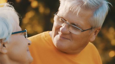 Yaşlılıkta sevgi ve şefkat. Emekli çift ormanda sonbahar gününün tadını çıkarıyor.