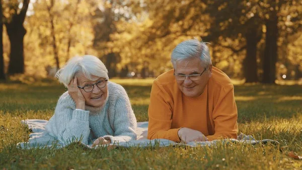 Concepto de bienestar. Retrato de feliz pareja jubilada mayor relajándose en el parque de otoño —  Fotos de Stock