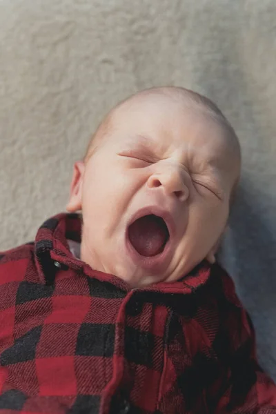 Sevimli yeni doğmuş bebek esniyor ve battaniyeye uzanıyor. — Stok fotoğraf