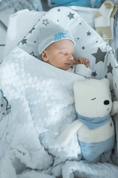 Adorável bebê recém-nascido dormindo pacificamente em seu berço no quarto do hospital com brinquedo macio — Fotografia de Stock