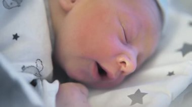 Sevimli yeni doğmuş bebek başını beşiğe kaldırmaya çalışıyor.