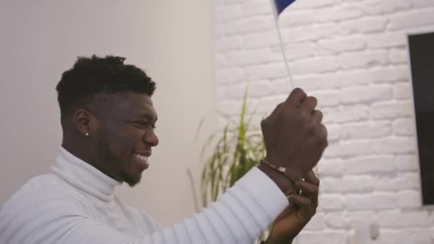 Czarny człowiek mający połączenie wideo lub oglądanie gry na smartfonie machając flagą Francji — Wideo stockowe