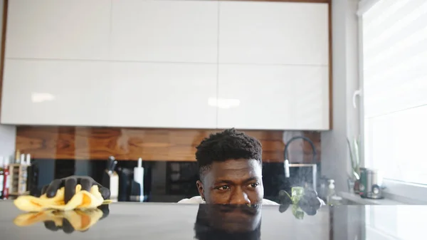 Siyah adam mutfağı temizliyor. Yüzey yüzünü yansıtıyor. — Stok fotoğraf