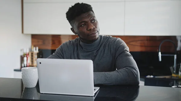 Joven afroamericano negro hombre trabajando en el ordenador portátil en su apartamento estiramiento y mirando a través de la ventana — Foto de Stock