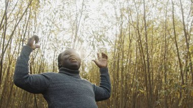 Doğada elini uzatan Afrikalı genç bir adam. Dua ya da kutlama.