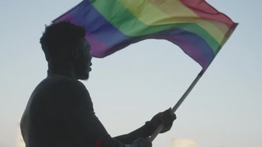 Siyah adam gökkuşağı bayrağı sallıyor. Cinsel kimlik ve eşit tedavi konsepti