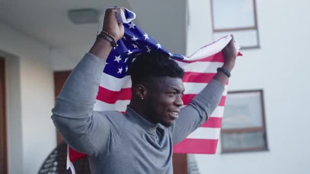 Homem negro acenando bandeira dos EUA da varanda — Vídeo de Stock