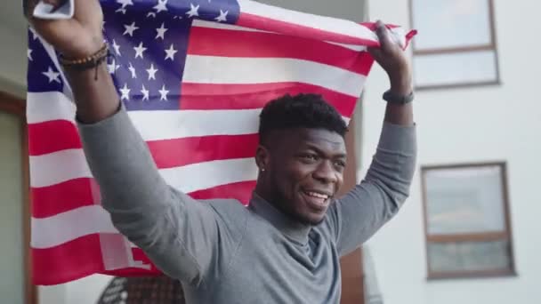Zwarte man zwaaiend met de vlag van de VS vanaf het balkon — Stockvideo