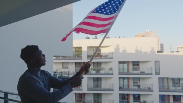 Homem negro acenando bandeira dos EUA da varanda — Vídeo de Stock