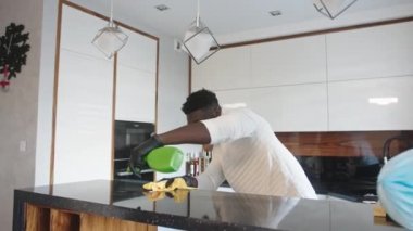 Siyah adam mutfak yüzeyine dezenfektan püskürtüyor. Germaphobe ev işi yapıyor.