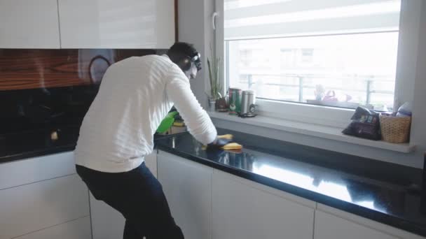 Feliz jovem negro ouvindo música e limpeza da superfície da cozinha — Vídeo de Stock