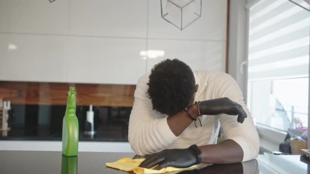 Unavený mladý černošky muž odpočívá na kuchyňské skříni při čištění — Stock video
