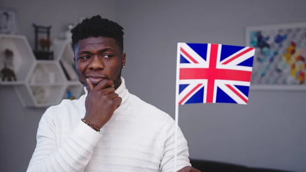 İngiltere bayrağını tutan düşünceli genç siyahi adam iş için göç etmeyi düşünüyor — Stok fotoğraf