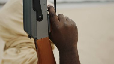 Kafası AK-47 makineli tüfekle çölde kaplanmış siyah bir adam.